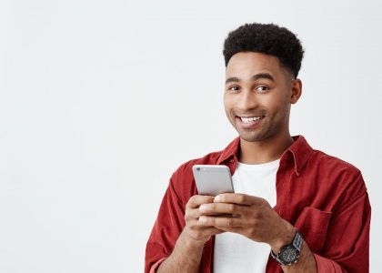 Rapaz sorrindo segurando celular